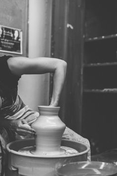 a woman is making a vase out of clay with her hands on the potter's wheel