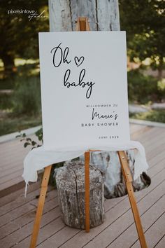 an easel with a sign that says oh baby on it sitting in front of a tree