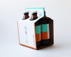 two brown and green bottles are in a cardboard box on a white surface, one is empty