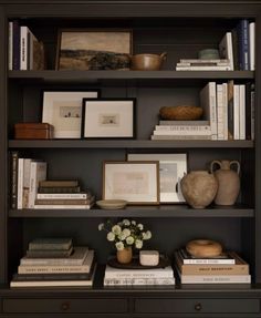 a bookshelf filled with lots of books and vases on top of it