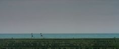 two people are walking along the beach near the ocean