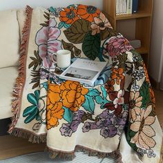 an open laptop computer sitting on top of a flowered blanket next to a couch