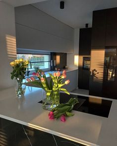 two vases filled with flowers sitting on top of a white counter next to a window