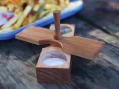 a wooden plane shaped salt and pepper shaker next to a plate of french fries