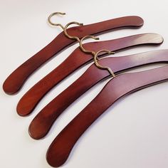 four pairs of wooden hangers with metal hooks attached to each one on a white surface