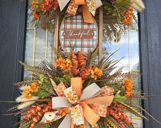 an orange and white fall wreath on the front door