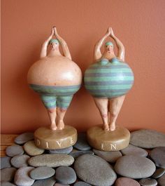 two figurines are standing on top of some rocks and one is doing yoga