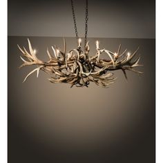 a chandelier made out of antlers hanging from a chain on a dark background