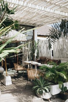 an outdoor patio with lots of plants and wicker furniture