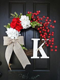 a wreath with the letter k on it and flowers hanging from it's front door