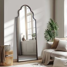 a living room with a couch, mirror and potted plant in front of the window