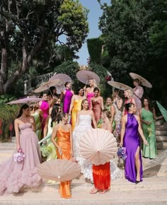 a group of women in dresses and parasols posing for a photo on the steps