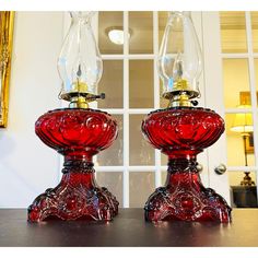 two red glass lamps sitting on top of a table