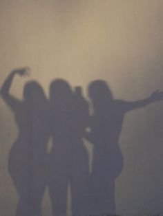 three women are standing in front of a wall with their arms spread out to the side