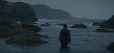 a man standing in the water looking out to sea