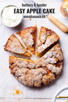 an apple cake with powdered sugar on top is cut into slices and sits on a white surface