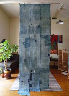 a living room with a large blue curtain hanging from the ceiling next to a potted plant