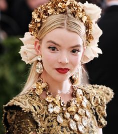 a woman with long blonde hair wearing a gold dress and flower headpiece in her hair