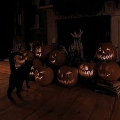 a black cat standing in front of pumpkins with carved faces on it's heads