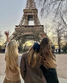 two girls standing in front of the eiffel tower, looking up at the sky