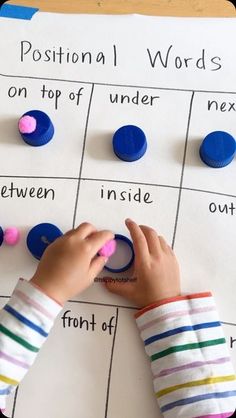 a child is playing with buttons on a piece of paper that says position words on top of it