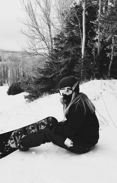 a person sitting in the snow with a snowboard