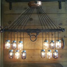 mason jar chandelier with lights hanging from it's sides on a wooden wall