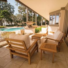 two wooden chairs sitting on top of a patio next to a swimming pool