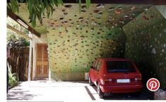 a red car is parked in front of a house with a decorative wall behind it