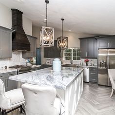 a large kitchen with marble counter tops and stainless steel appliances, along with two white chairs