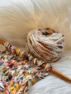 a ball of yarn sitting on top of a white blanket next to a knitting needle