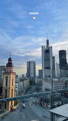 a city with tall buildings and a clock tower in the center, under a blue cloudy sky