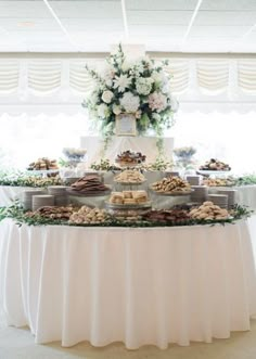 a table topped with lots of desserts next to a white flower filled window sill