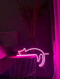 a pink neon cat sitting on top of a table