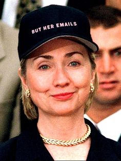 a woman wearing a hat and smiling at the camera with other people in the background