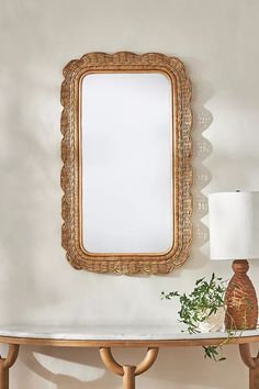 a mirror sitting on top of a wooden table next to a lamp and potted plant