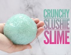 a hand holding a green bath ball with the words crunchy slushie slime on it