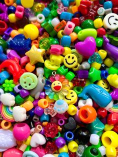 there are many different colored beads and toys in this pile, including one with a smiley face on it