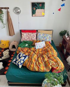 an unmade bed with many pillows and blankets on it in a room filled with stuffed animals