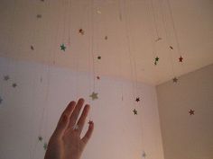 a hand reaching up to the ceiling with stars hanging from it's ceiling line