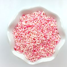 pink sprinkles in a white bowl on a white surface