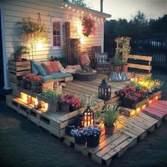 an outdoor deck with lights and potted plants on the top, surrounded by wooden pallets