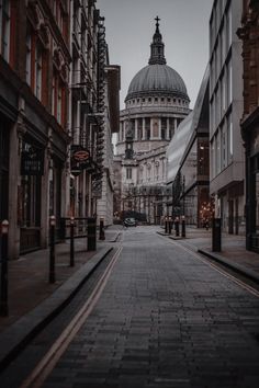 an empty city street with buildings on both sides and a domed building in the background