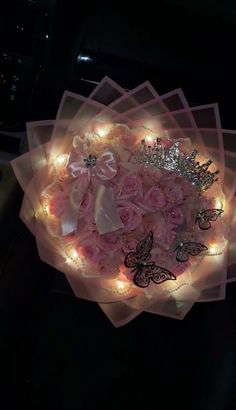 pink roses and butterflies are arranged in a bouquet with fairy lights on the side for decoration