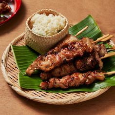 a plate with meat and rice on it next to some chopsticks in a basket