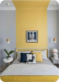 a bedroom with yellow walls, white bedding and two hanging lights above the bed