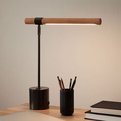 a desk with a lamp, pencils and books on it