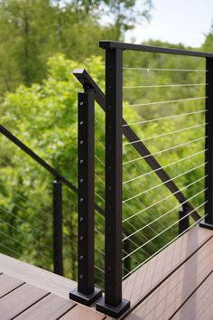 a black metal railing on a wooden deck with trees in the background and bushes behind it