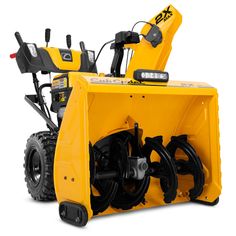 a yellow snow blower sitting on top of a white floor next to a black wheel