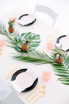 the table is set with pineapples, plates and place settings for two people